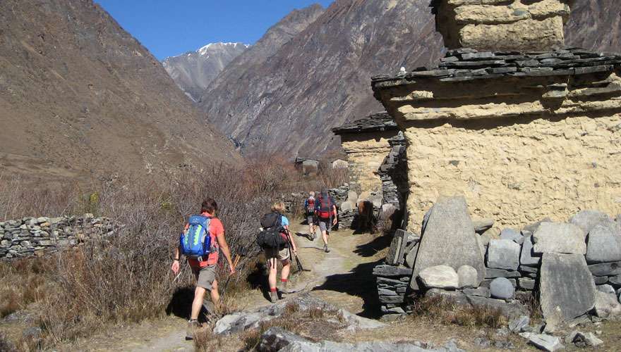 Trekkers walk by a Buddhist monument in Tsum Valley